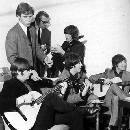 I Beatles nel febbraio 1965. Ringo Starr con chitarra a sinistra, poi George Harrison con sotto Paul Mc Cartney, John Lennon a destra. Con loro nella foto i due road manager e amici, in piedi: Neil Aspinall davanti con cravatta e giacca grigia, Mal Evas dietri che guarda George, con occhiali neri spessi.