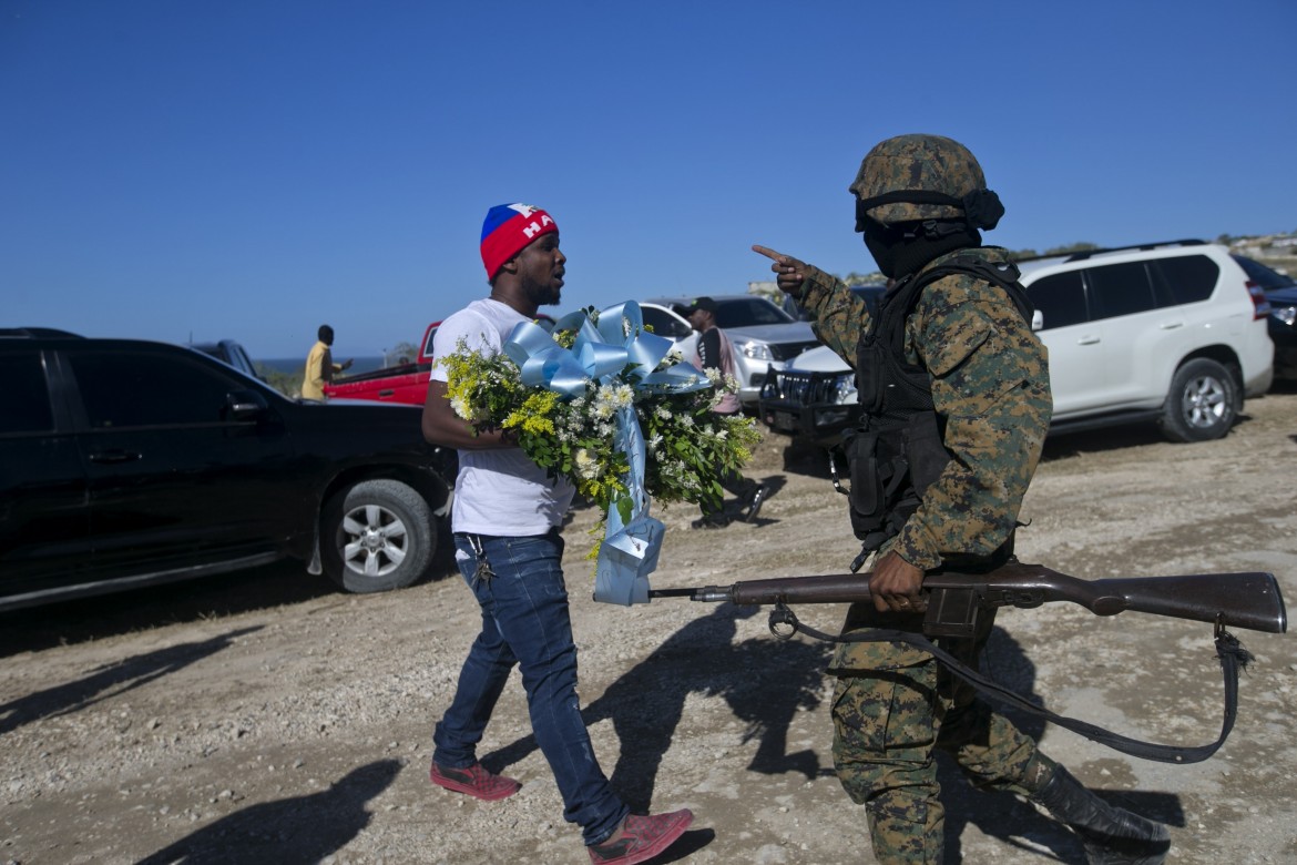 Haiti, 12 gennaio. Un uomo tenta invano di deporre una corona di fiori a Titanyen, la collina dove sono sepolti i morti senza nome del terremoto 2010