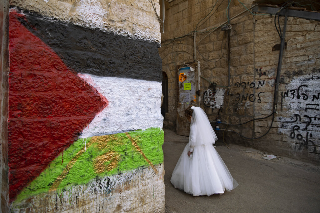 Gerusalemme. Una sposa ebrea passa accanto a un muro con una bandiera palestinese