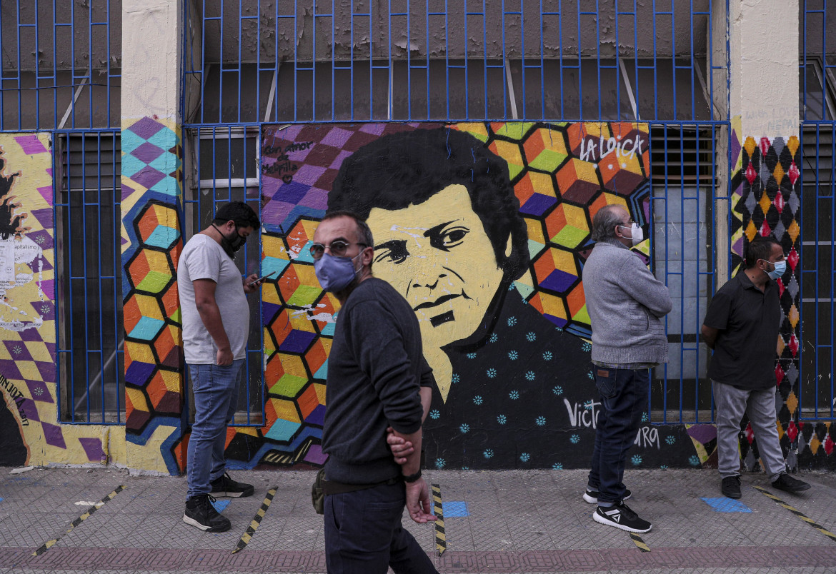 In fila per votare a Santiago di fronte a un murale dedicato a Victor Jara, indimenticato cantautore comunista ucciso dal regime di Pinochet
