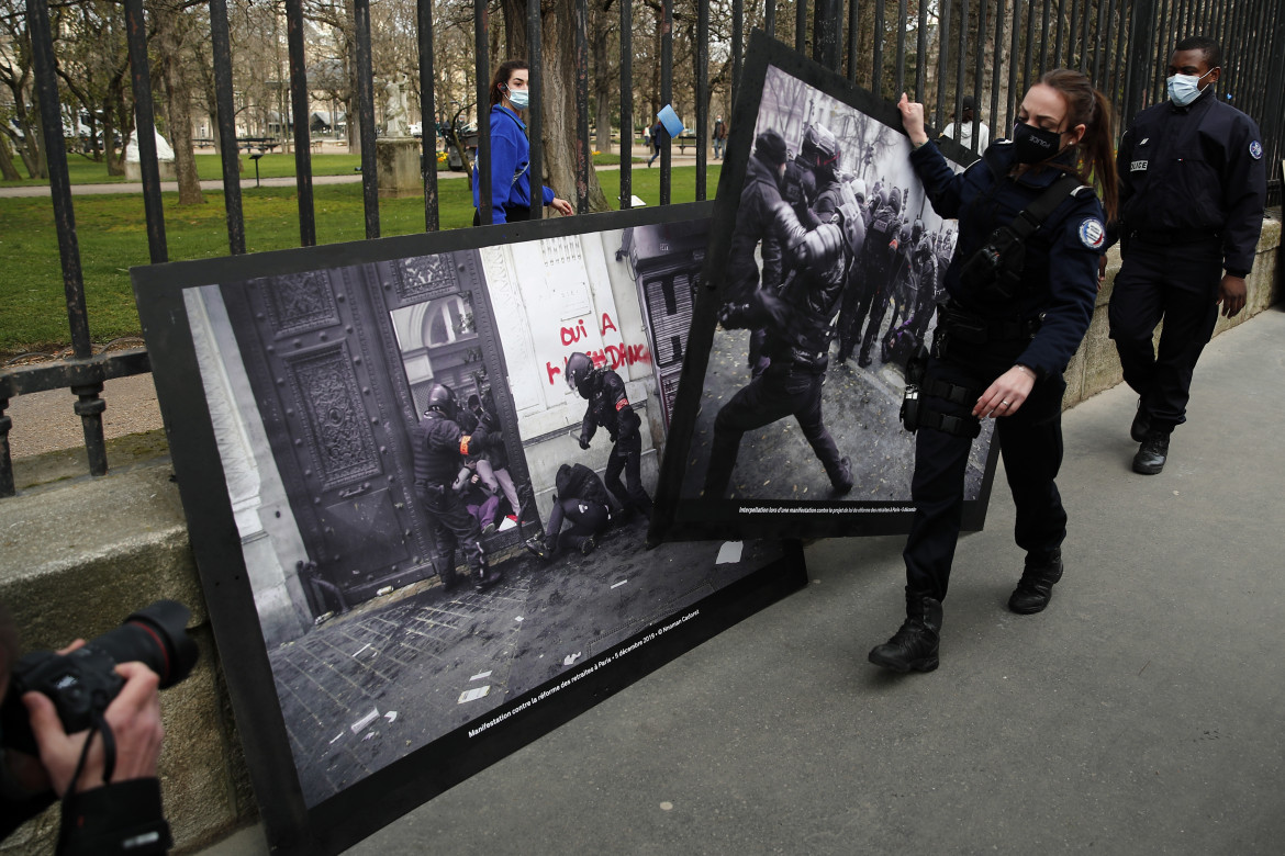 Agenti rimuovono le foto della violenza della polizia appese dagli attivisti di Attac e Greenpeace